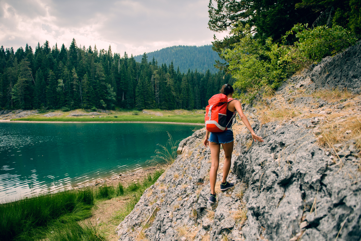 woman hiking on mountain with a lake in the backdrop