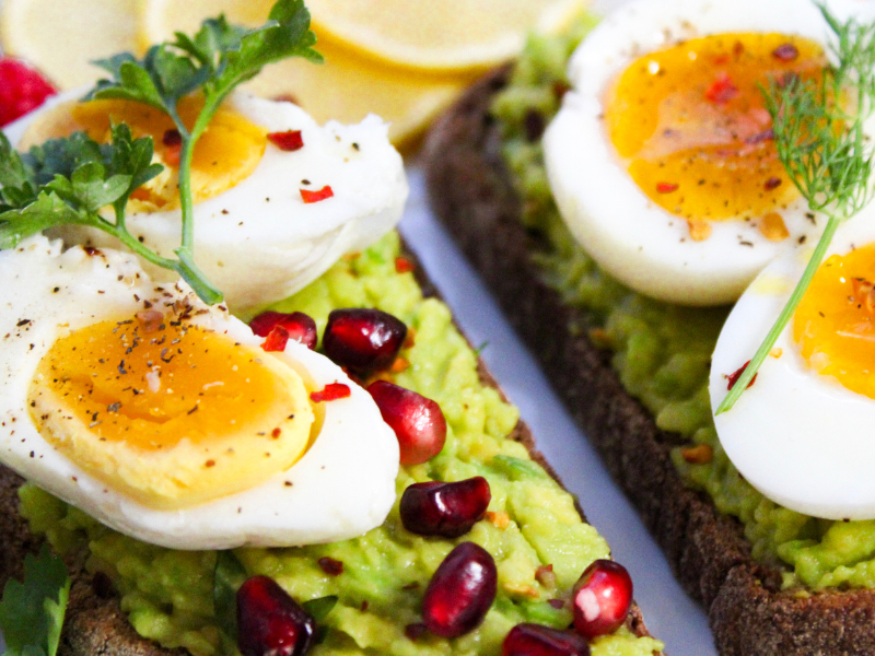 Healthy protein rich breakfast of eggs, avocado and pomegranate on healthy bread