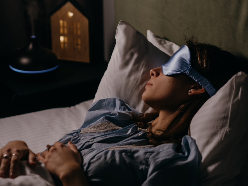 Woman sleeping in bed wearing a sleep mask