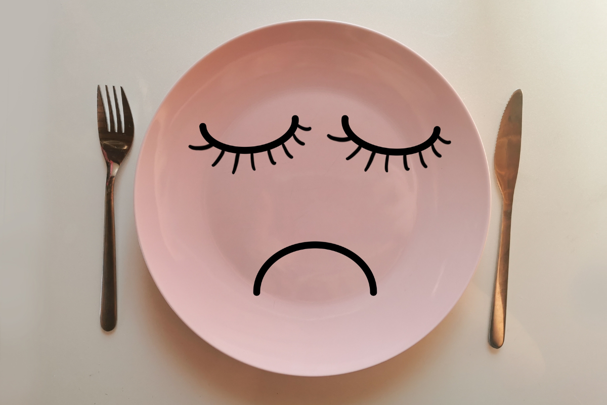 Empty plate with sad face and knife and fork on the sides