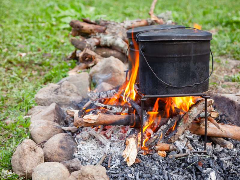 Pot cooking on an open fire outside with stones and grass around