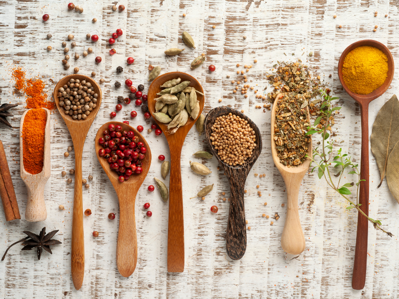 Different spices on wooden spoons on top of a linen cloth