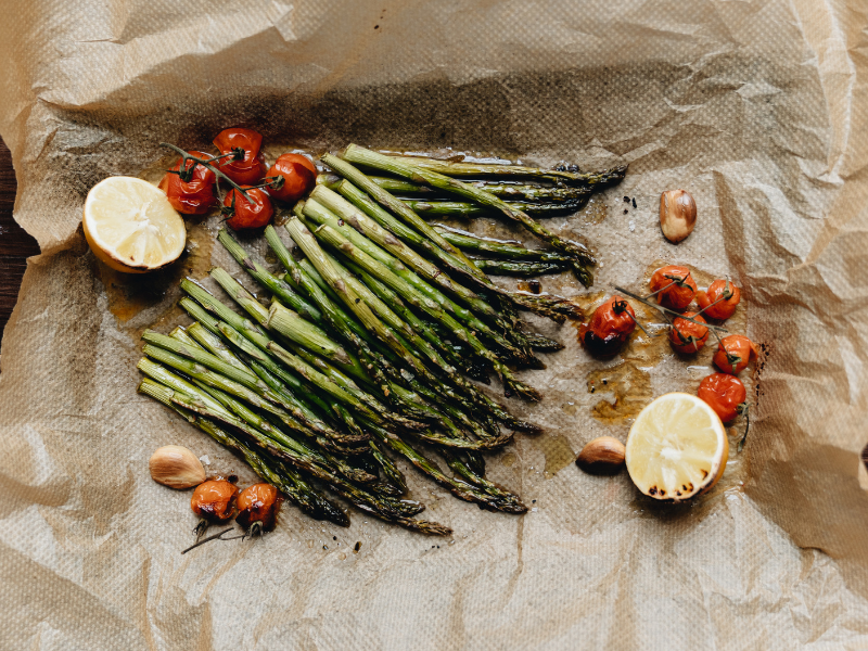 Chargrilled asparagus and tomatoes on baking paper with lemons